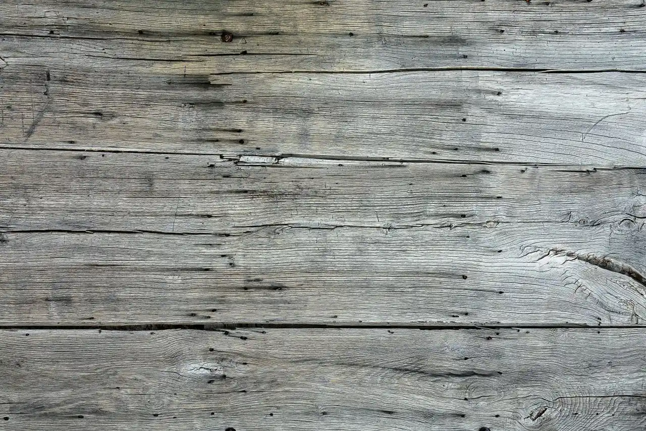 Close-up of weathered timber boards with visible grain, cracks, and old nail holes
